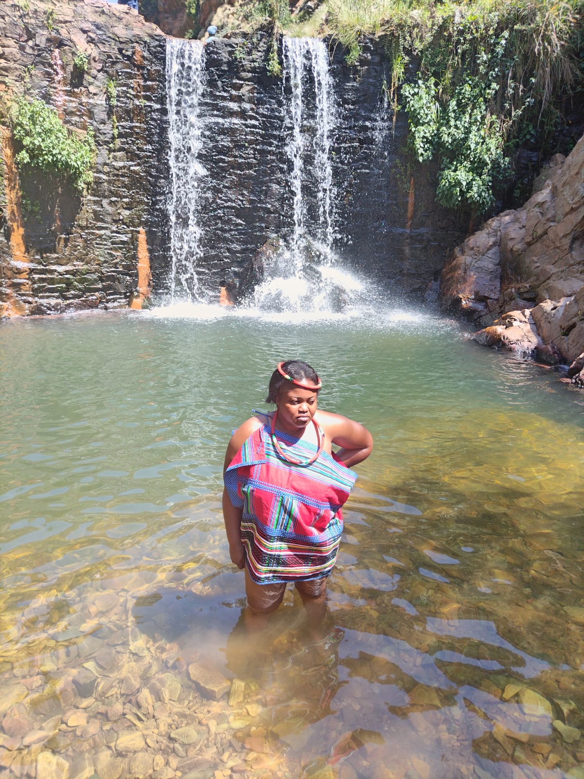 Embracing the natural elements, a Sangoma performs rituals and ceremonies by the river, harnessing the power of water for purification and spiritual cleansing.